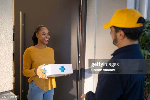 delivery person delivering medicine to woman - prescription home delivery stock pictures, royalty-free photos & images