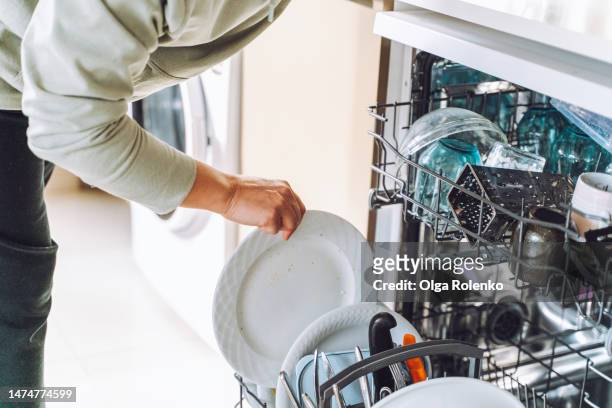 easy to use domestic appliances. cropped woman get clean crockery, unloading dishwasher machine in the light kitchen - easy load stock pictures, royalty-free photos & images
