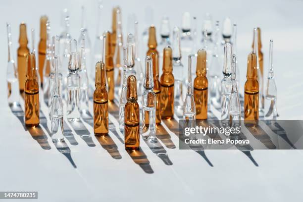 set of white and bronze transparent ampoules against sun and shadows background - ampoule stock-fotos und bilder