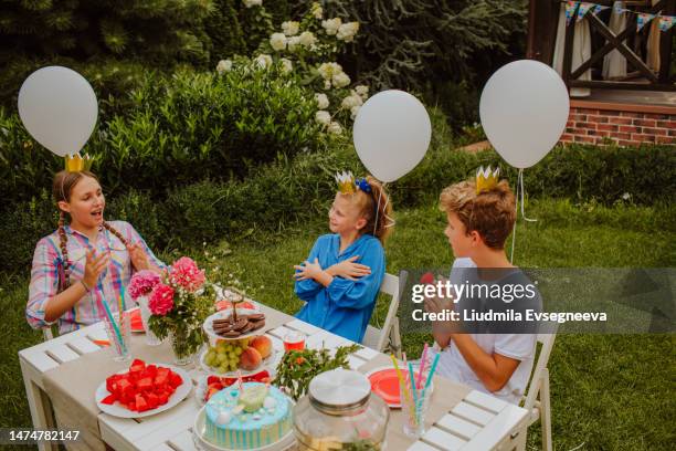 kids are sitting near decorated birthday table in home yard. - all age party stock pictures, royalty-free photos & images