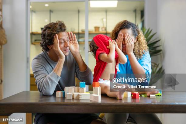 interactive games and fun activities can help in a child’s development. father and mother playing hide-and-seek or peek-a-boo games with their daughter in the living room at home. - emotional intelligence stockfoto's en -beelden