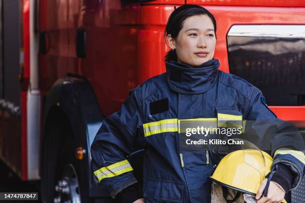 asian female firefighter standing holding her helmet - chinese hero bildbanksfoton och bilder