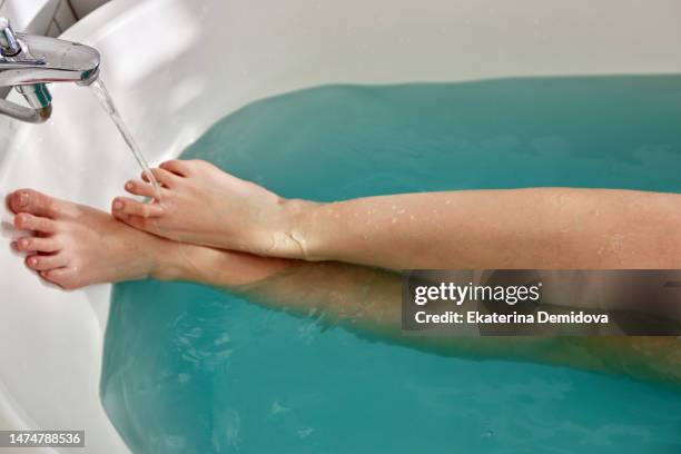 crop woman in bathtub with leg on tap - shivering house stock pictures, royalty-free photos & images