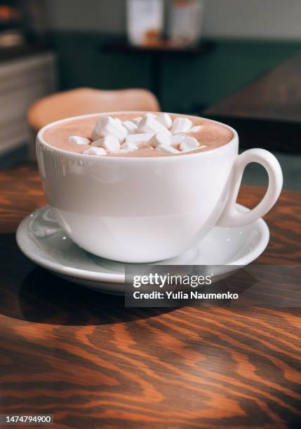 a cup with hot chocolate and marshmallows on a table in a cafe. - hot chocolate stock pictures, royalty-free photos & images