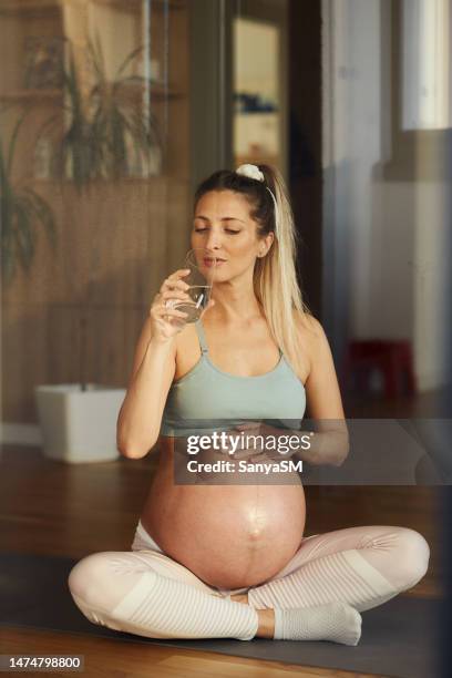 warten auf eine schwangere frau, die wasser trinkt - schneidersitz stock-fotos und bilder