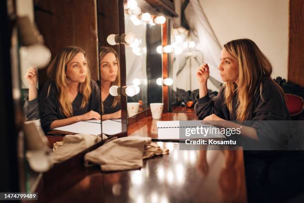 die schauspielerin in der garderobe probt die szene vor dem spiegel sitzend vor der aufführung - boudoir stock-fotos und bilder