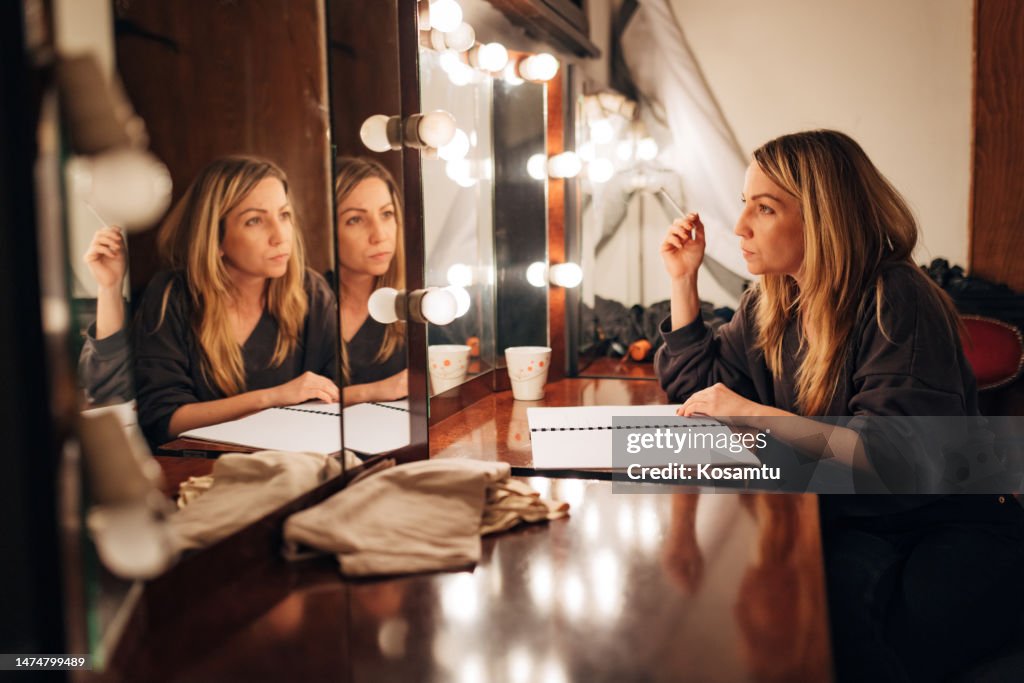 The actress in the dressing room rehearses the scene sitting in front of the mirror before the performance