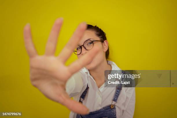 portrait of a woman covering the camera with her hand and hiding from it - woman shielding face stock pictures, royalty-free photos & images