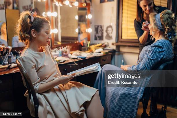 actress in costume rehearses the text of a play as she sits next to an older actress preparing for a performance - woman backstage stock pictures, royalty-free photos & images