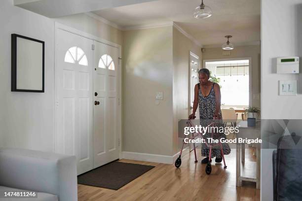 senior woman walking with mobility walker at home - mobility walker stock pictures, royalty-free photos & images