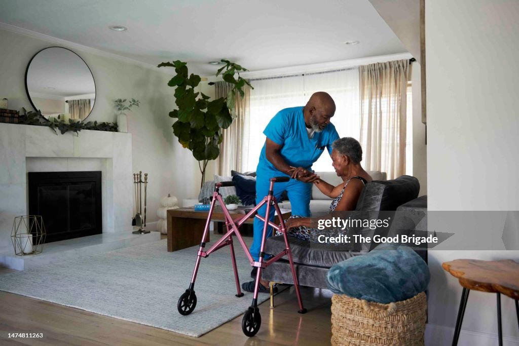 Male healthcare worker helping senior woman sit in chair