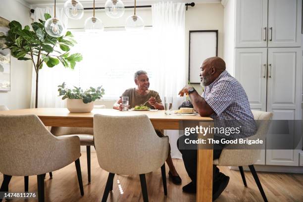 mother and son discussing with each other while having lunch at dining table in home - chair stock pictures, royalty-free photos & images