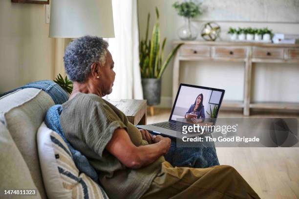senior female patient taking online consultation with doctor through laptop at home - telemedicine foto e immagini stock
