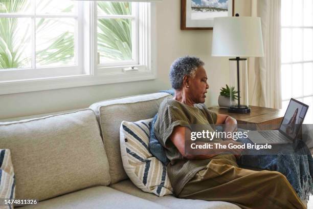 senior woman consulting female doctor through video call using laptop at home - medicare fotografías e imágenes de stock