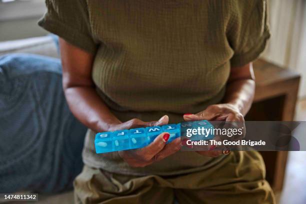 midsection of senior woman holding pill box at home - pill container stock pictures, royalty-free photos & images