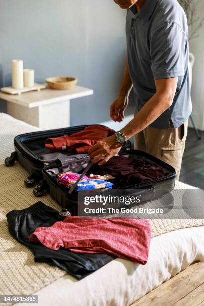 midsection of man organizing clothes in suitcase on bed - packing stock pictures, royalty-free photos & images
