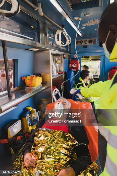 elder man in ambulance with oxygen mask - foil blanket stock pictures, royalty-free photos & images