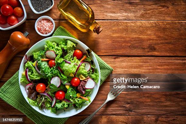 top view of fresh and healthy salad in a bowl on wooden table - radijs stockfoto's en -beelden