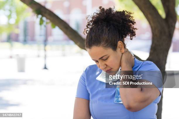 exhausted female nurse rubs neck after long shift - nurse praying stock pictures, royalty-free photos & images