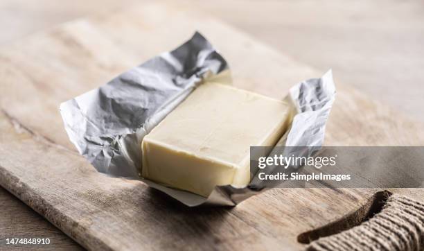 whole butter unwrapped and placed on the cutting board - close - up. - margarina fotografías e imágenes de stock