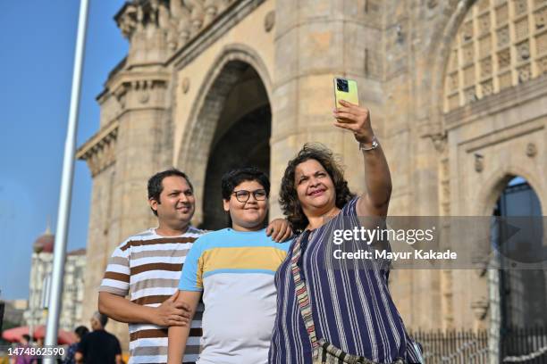 tourist mid adult woman clicking selfie with her family standing at the harbour at gateway of india, mumbai city - father clicking selfie bildbanksfoton och bilder