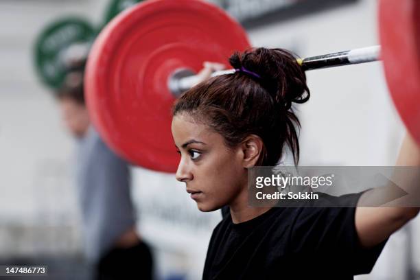 young woman training with weights - weightlifting stock-fotos und bilder