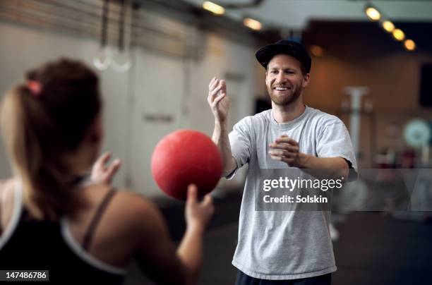 man and woman training with ball at gym - catching ball stock pictures, royalty-free photos & images