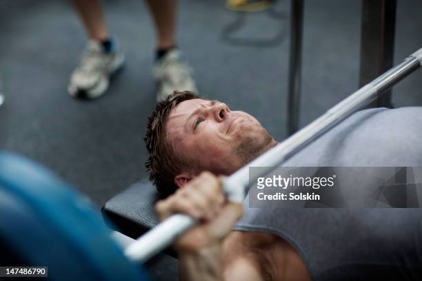 man doing benchpress in gym - weightlifting stock-fotos und bilder