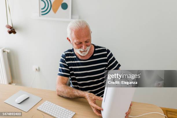 senior man in a new home who assembles humidifier - air freshener stock pictures, royalty-free photos & images