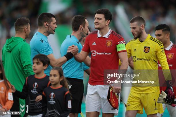 Harry Maguire captain of Manchester United is followed by team mates David De Gea and Casemiro tas he shakes hands with the officials and opponents...