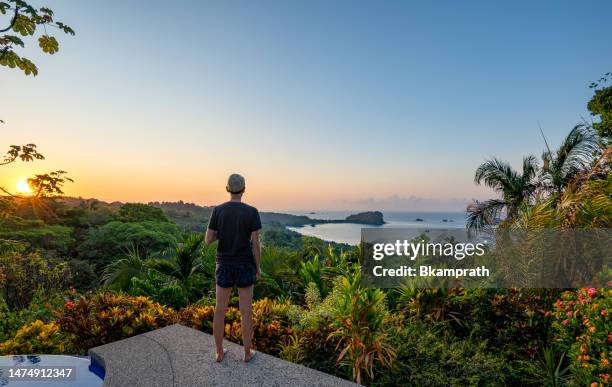 woman enjoying a vibrant sunrise over the wild untamed coastal beauty of manuel antonio national park on the pacific coast of costa rica - pacific ocean stock pictures, royalty-free photos & images