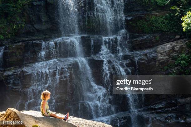 toddler girl enjoying the beautiful nauyaca waterfall in the wild untamed coastal beauty of the pacific coast of costa rica - costa rica waterfall stock pictures, royalty-free photos & images