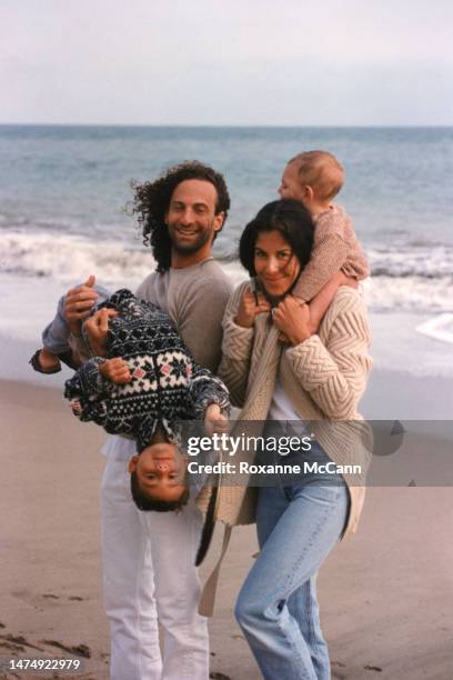 Saxophonist Kenny G holds his son Max Gorelick while walking with his wife Lyndie Benson who is holding their son Noah Gorelick on the beach in 1998...