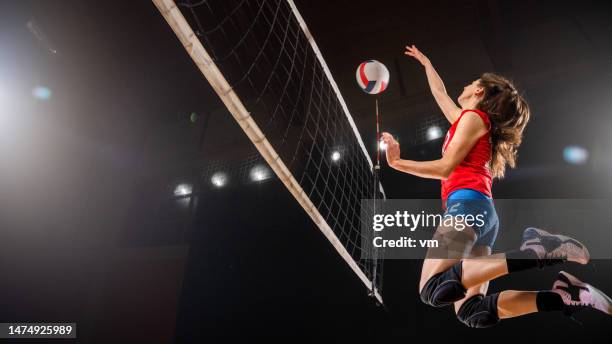 volleyballspielerin kickt ball durch das netz - volleyball stock-fotos und bilder