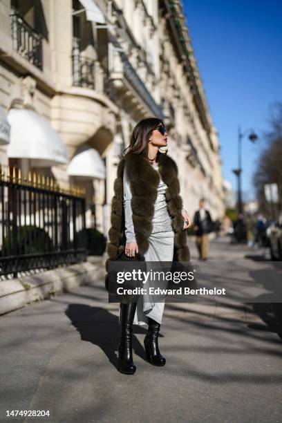 Heart Evangelista wears heart-shaped sunglasses, a green khaki faux fur long winter coat, a silver shiny glitter ruffled midi slit dress / gown from...