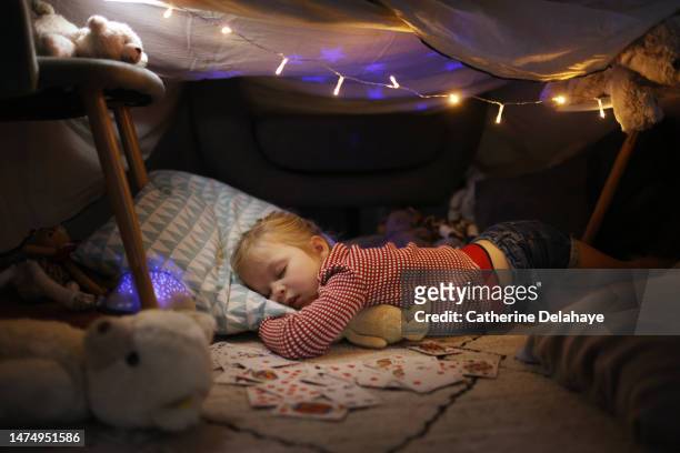 a little girl sleeping in a homemade illuminated hut, at home - child in space suit stock pictures, royalty-free photos & images