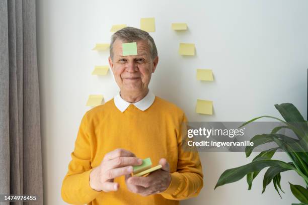 businessman with sticky note sticking at his forehead in office - mot photos et images de collection