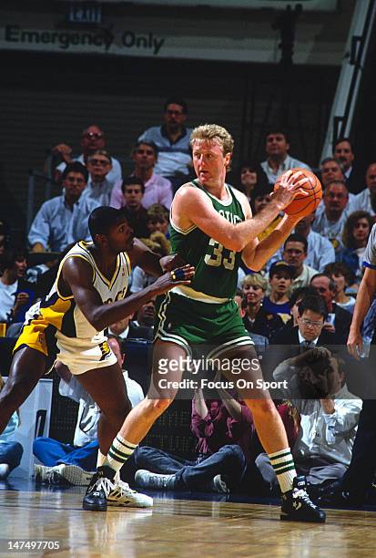 Larry Bird of the Boston Celtics looks to put a move on an Indiana Pacers defender during an NBA basketball game circa 1991 at Market Square Arena in...