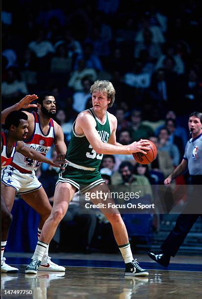 Larry Bird of the Boston Celtics looking to pass over Frank Johnson and Greg Ballard of the Washington Bullets during an NBA basketball game circa...