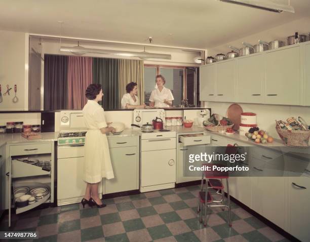 Ruth Morgan, cookery editor of Woman Magazine, stands on right with assistants Esme Fox, in centre, and Margaret Galloway, on left, in a modern...
