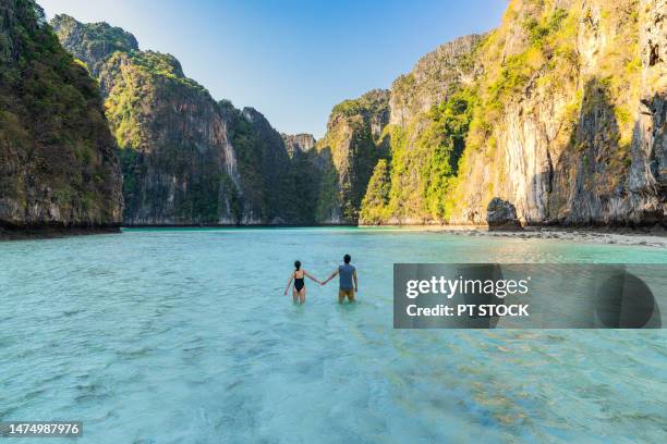 male and female couple standing at pileh lagoon bay it is a small bay in koh phi phi. which is surrounded by many mountains, is a place that tourists like very much whether the tide is high or low, it's still beautiful, krabi, thailand. - phuket photos et images de collection