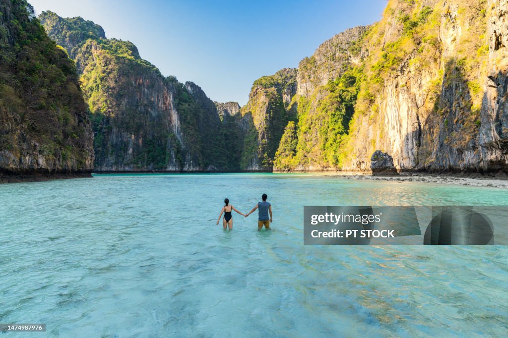 Male and female couple standing at Pileh Lagoon Bay It is a small bay in Koh Phi Phi. which is surrounded by many mountains, is a place that tourists like very much Whether the tide is high or low, it's still beautiful, Krabi, Thailand.