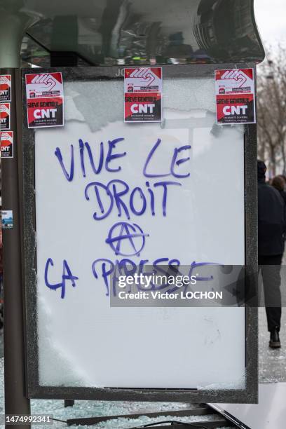 Panneau d'affichage lumineux d'un abri-bus vandalisé avec une inscription anarchiste "Vive le droit de la paresse" et autocollants CNT lors de la...