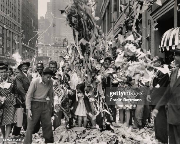 People in New York's Garment Center celebrate the news of Italy's surrender as ticker-tape is being thrown from windows above on September 8th, 1943.