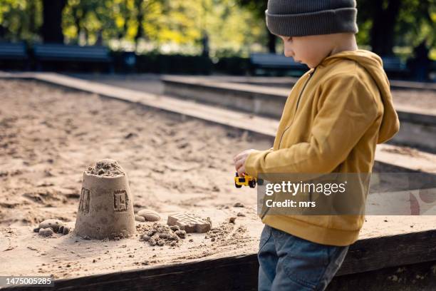 little boy playing in sandbox on a playground - sandkasten stock-fotos und bilder