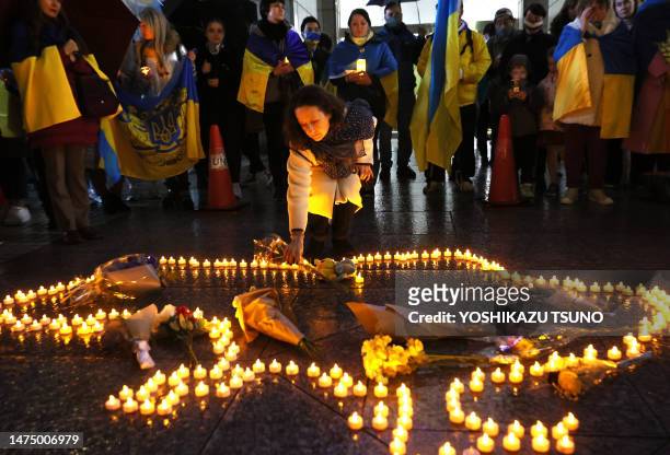 Une résidente ukrainienne place un bouquet de fleurs au milieu de bougies LED formant le contour de la frontière ukrainienne pour marquer le premier...
