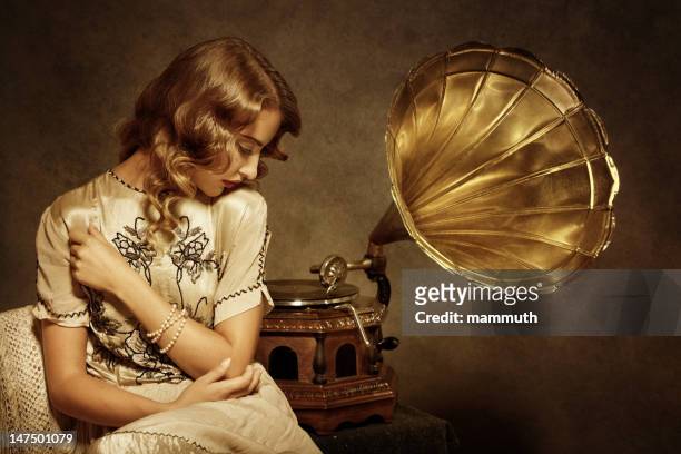 retro woman listening to music on gramophone - 20s stockfoto's en -beelden