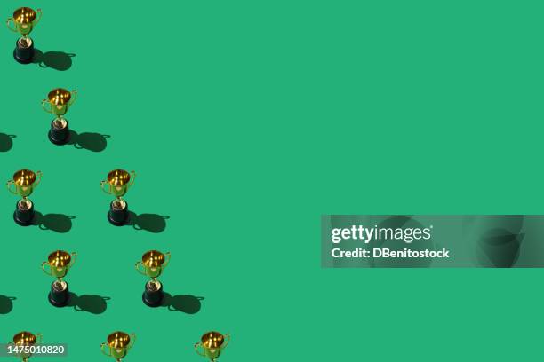 gold winner cup trophy pattern with hard shadow, on the left side, on green background. concept of winner, victory, victor. - fellow soldier stock pictures, royalty-free photos & images