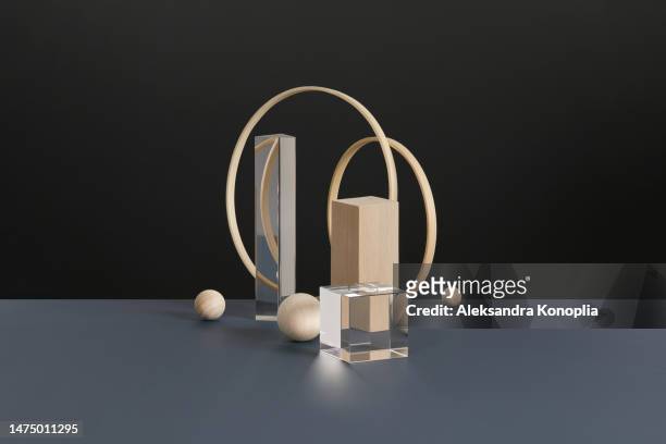 abstract minimal 3d scene showcase with geometric composition of natural wooden circles, block, balls and glass prism and cube on dark gray and black background. - black cube stock pictures, royalty-free photos & images