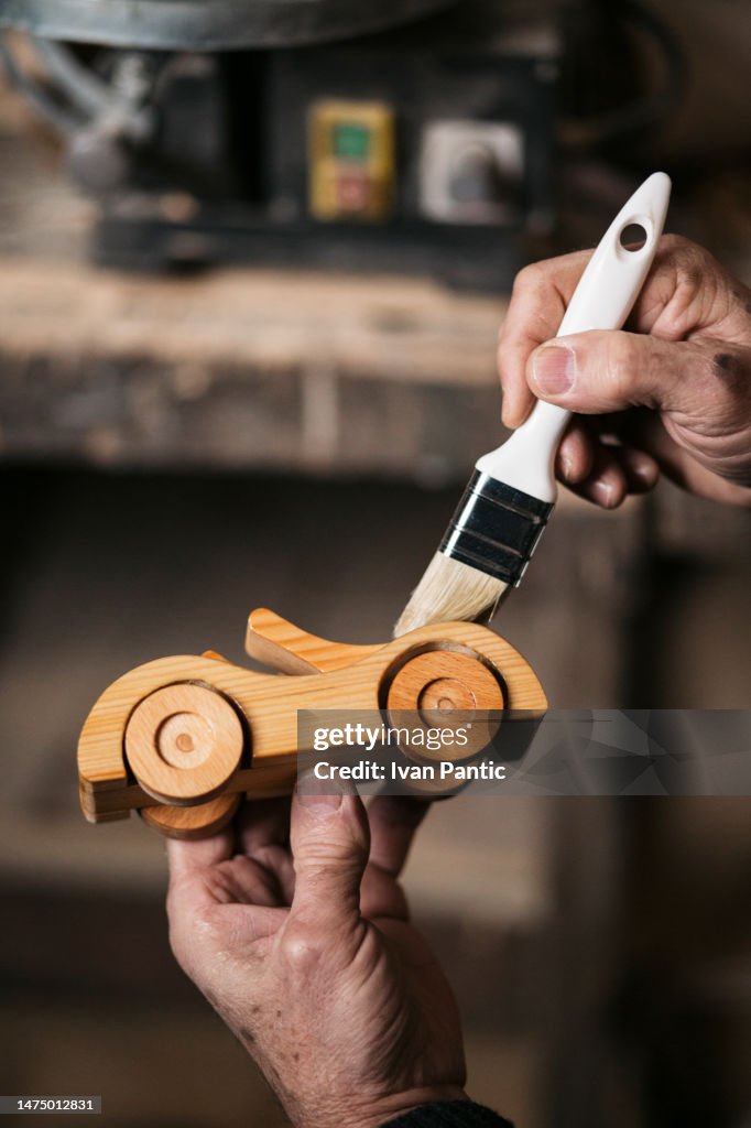 Close up of protecting a wooden car toy with varnish.